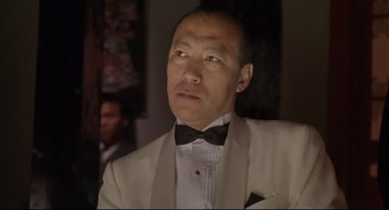 Movie still from “Double Impact” (1991), directed by Sheldon Lettich – A person wearing a suit and a bow tie; Close Up shot, Low angle