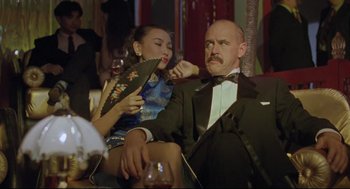 Movie still from “Double Impact” (1991), directed by Sheldon Lettich – A man and a woman sitting on a couch; Medium shot, Low angle