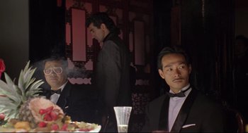 Movie still from “Double Impact” (1991), directed by Sheldon Lettich – A man smoking a cigarette at a dinner table; Medium shot, Low angle
