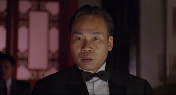 Movie still from “Double Impact” (1991), directed by Sheldon Lettich – A person wearing a suit and a bow tie; Close Up shot, Low angle