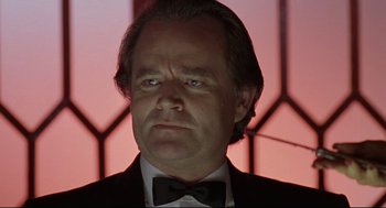 Movie still from “Double Impact” (1991), directed by Sheldon Lettich – A person wearing a suit and bow tie; Close Up shot, Low angle