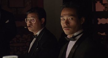 Movie still from “Double Impact” (1991), directed by Sheldon Lettich – A couple of men standing next to each other in tuxedos; Medium shot, Low angle