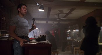 Movie still from “Double Impact” (1991), directed by Sheldon Lettich – A man holding a phone up to his ear in a restaurant; Medium shot, Low angle