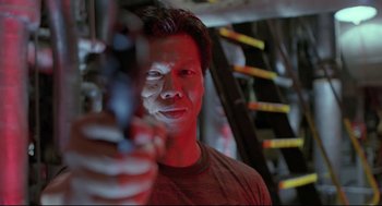 Movie still from “Double Impact” (1991), directed by Sheldon Lettich – A man holding a gun in a room with red lighting; Close Up shot, Low angle