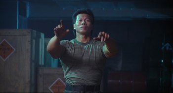 Movie still from “Double Impact” (1991), directed by Sheldon Lettich – A man is holding his hands up in the air; Medium shot, Low angle