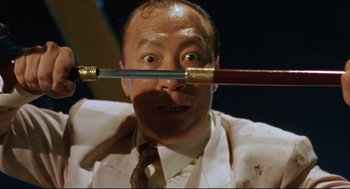 Movie still from “Double Impact” (1991), directed by Sheldon Lettich – A man holding a pair of pencils in front of his face; Close Up shot, Low angle