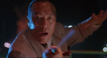 Movie still from “Double Impact” (1991), directed by Sheldon Lettich – A person holding a cell phone; Close Up shot, Low angle