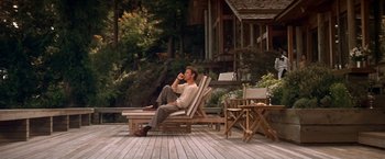 Movie still from “Double Jeopardy” (1999), directed by Bruce Beresford – A man sitting in a chair on a deck drinking a beverage; Wide shot, High angle