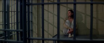 Movie still from “Double Jeopardy” (1999), directed by Bruce Beresford – A woman sitting on a bench in a jail cell; Wide shot, High angle