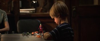 Movie still from “Double Jeopardy” (1999), directed by Bruce Beresford – A young boy sitting at a table playing with toys; Medium shot, High angle