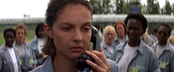 Movie still from “Double Jeopardy” (1999), directed by Bruce Beresford – A woman on a cell phone in front of a group of people; Close Up shot, Over the shoulder angle