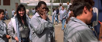 Movie still from “Double Jeopardy” (1999), directed by Bruce Beresford – A woman smoking a cigarette in front of a group of people; Medium shot, High angle