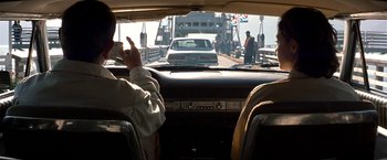 Movie still from “Double Jeopardy” (1999), directed by Bruce Beresford – A car driving on a bridge while people are standing on the bridge; Medium shot, Over the shoulder angle