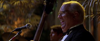 Movie still from “Double Jeopardy” (1999), directed by Bruce Beresford – An older man smiles while holding a guitar in front of a microphone; Close Up shot, Low angle
