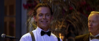 Movie still from “Double Jeopardy” (1999), directed by Bruce Beresford – A man wearing a bow tie and suspenders smiling; Close Up shot, Low angle