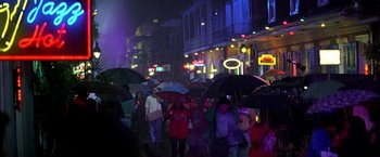 Movie still from “Double Jeopardy” (1999), directed by Bruce Beresford – A group of people walking down a street at night with umbrellas; Extreme Wide shot, High angle