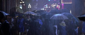 Movie still from “Double Jeopardy” (1999), directed by Bruce Beresford – A group of people walking down a street in the rain with umbrellas; Wide shot, High angle