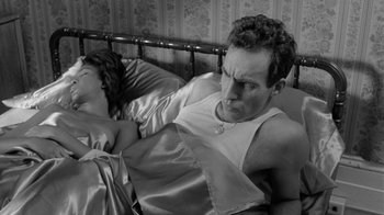 Movie still from “Down by Law” (1986), directed by Jim Jarmusch – A man and a woman laying in a bed together; Medium shot, High angle