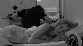 Movie still from “Down by Law” (1986), directed by Jim Jarmusch – A woman laying on a bed with a man standing over her; Medium shot, High angle
