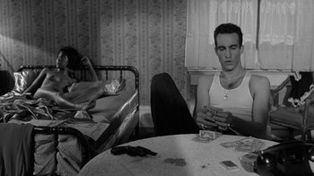 Movie still from “Down by Law” (1986), directed by Jim Jarmusch – A man sitting at a table playing cards with a woman; Medium shot, High angle