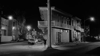 Movie still from “Down by Law” (1986), directed by Jim Jarmusch – A black and white photo of a person standing on the sidewalk; Extreme Wide shot, Low angle