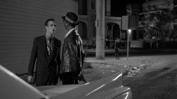 Movie still from “Down by Law” (1986), directed by Jim Jarmusch – A couple of men standing next to each other on the street; Medium shot, Over the shoulder angle