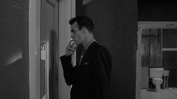 Movie still from “Down by Law” (1986), directed by Jim Jarmusch – A black and white photo of a man drinking a glass of wine; Medium shot, Over the shoulder angle