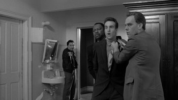 Movie still from “Down by Law” (1986), directed by Jim Jarmusch – A group of men in a room with a mirror; Medium shot, Over the shoulder angle