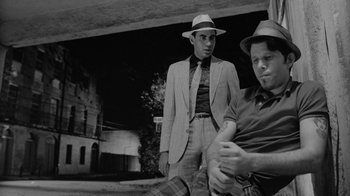 Movie still from “Down by Law” (1986), directed by Jim Jarmusch – Two men in hats and suits standing next to each other; Medium shot, Low angle