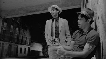 Movie still from “Down by Law” (1986), directed by Jim Jarmusch – A man in a suit and a hat standing next to another man in a hat; Medium shot, Low angle