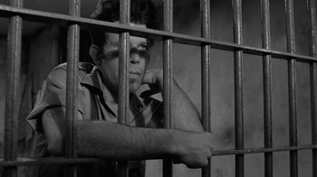 Movie still from “Down by Law” (1986), directed by Jim Jarmusch – A man sitting behind bars in a jail cell; Medium shot, Low angle