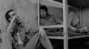 Movie still from “Down by Law” (1986), directed by Jim Jarmusch – A black and white photo of a man sitting on a bunk bed; Medium shot, Low angle