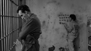 Movie still from “Down by Law” (1986), directed by Jim Jarmusch – A man standing in front of a wall with graffiti on it; Medium shot, Low angle