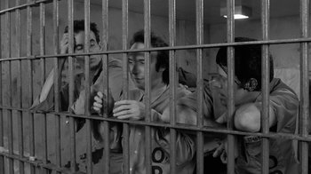Movie still from “Down by Law” (1986), directed by Jim Jarmusch – A group of men standing behind a metal fence; Medium shot, High angle
