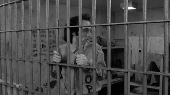 Movie still from “Down by Law” (1986), directed by Jim Jarmusch – A man standing behind bars in a jail cell; Medium shot, Low angle