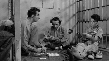 Movie still from “Down by Law” (1986), directed by Jim Jarmusch – A group of men sitting on the ground playing a game; Medium shot, High angle