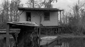 Movie still from “Down by Law” (1986), directed by Jim Jarmusch – An old boat sits in front of a house on stilts; Wide shot, Low angle