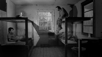 Movie still from “Down by Law” (1986), directed by Jim Jarmusch – A man jumping on top of bunk beds in a room; Wide shot, Low angle