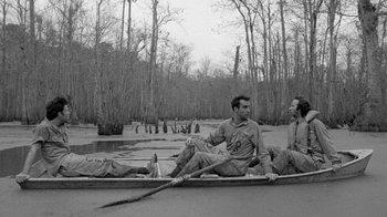 Movie still from “Down by Law” (1986), directed by Jim Jarmusch – A group of men sitting in a row boat on a body of water; Wide shot, High angle