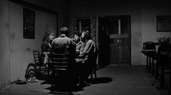Movie still from “Down by Law” (1986), directed by Jim Jarmusch – A group of people sitting around a table; Wide shot, High angle