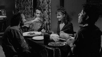 Movie still from “Down by Law” (1986), directed by Jim Jarmusch – A group of people sitting around a table eating; Medium shot, High angle