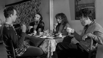Movie still from “Down by Law” (1986), directed by Jim Jarmusch – A group of people sitting at a table drinking coffee; Medium shot, Over the shoulder angle