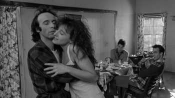 Movie still from “Down by Law” (1986), directed by Jim Jarmusch – A man and a woman kissing in front of a table; Medium shot, Over the shoulder angle