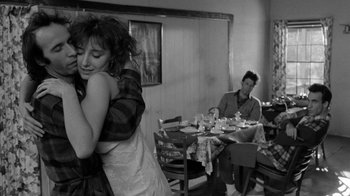 Movie still from “Down by Law” (1986), directed by Jim Jarmusch – A man and a woman hugging in a dining room; Medium shot, Over the shoulder angle