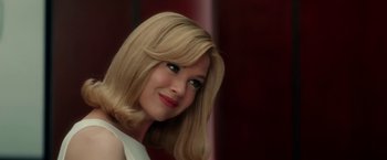 Movie still from “Down with Love” (2003), directed by Peyton Reed – A woman with blonde hair and blue eyes smiling for the camera; Close Up shot, Over the shoulder angle
