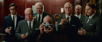 Movie still from “Down with Love” (2003), directed by Peyton Reed – A man taking a picture of a group of men drinking wine; Medium shot, Low angle