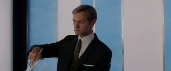 Movie still from “Down with Love” (2003), directed by Peyton Reed – A man wearing a suit and tie standing in front of a window; Medium shot, Low angle