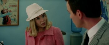 Movie still from “Down with Love” (2003), directed by Peyton Reed – A woman wearing a pink coat and a white hat; Close Up shot, Over the shoulder angle