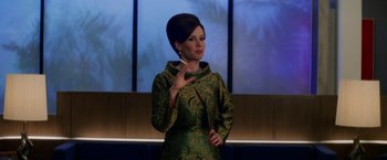 Movie still from “Down with Love” (2003), directed by Peyton Reed – A woman in a green dress is standing in front of a window; Medium shot, Over the shoulder angle