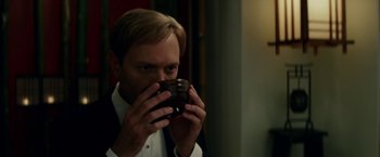 Movie still from “Down with Love” (2003), directed by Peyton Reed – A man in a suit drinking a cup of coffee; Close Up shot, Over the shoulder angle